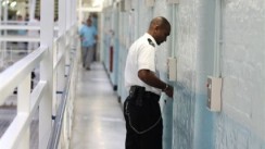 A prison officer standing outside a prison cell on a wing